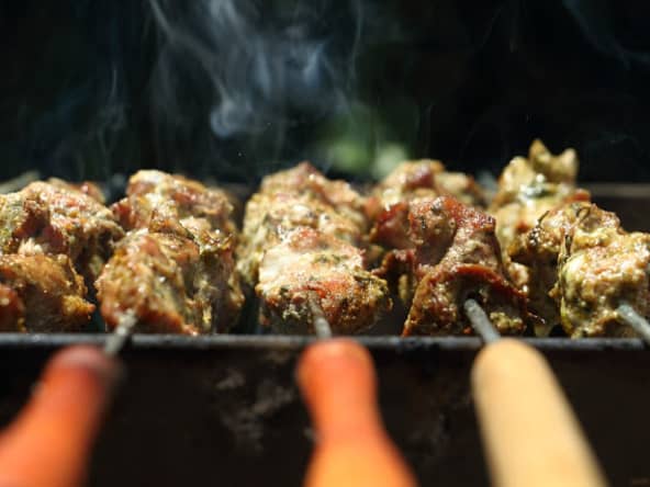 Brochettes de porc au thym garnies de tomates et d'oignons grillés