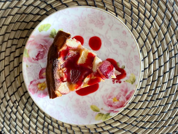 Clafoutis aux pêches servi tiède avec un coulis de framboises frais