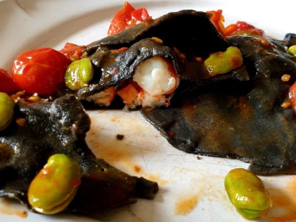 Ravioli noirs aux gambas avec fèves et tomates