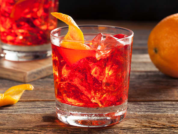 Cocktail Negroni dans un verre, sur une planche avec une orange
