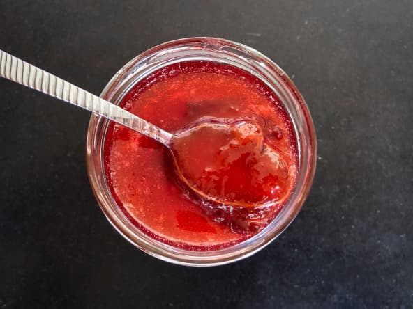 Cuillère dans un bocal de confiture de prunes rouges