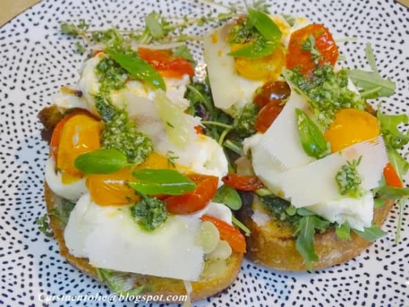Bruschetta au pesto maison, mozzarella, roquette, tomates cerises rôties et grana padano