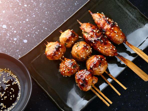 Tsukune sur fond noir et bol de sauce