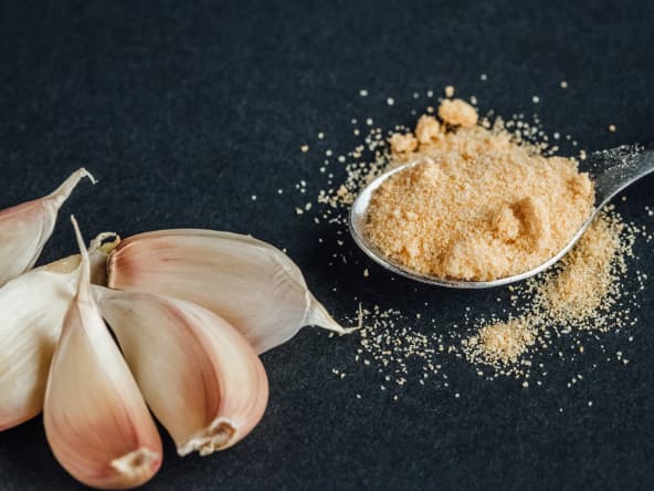 Gousses d'ail et ail en poudre dans une petite cuillère