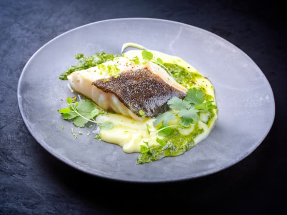 Filet de cabillaud et sauce verte sur assiette grise.