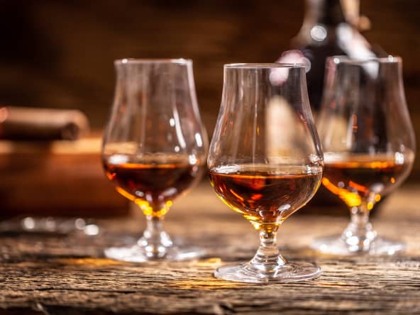 3 verres de rhum brun sur table en boie
