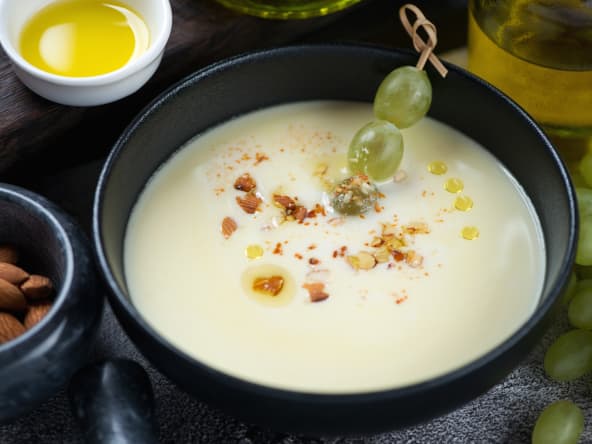 Ajoblanco dans un bol noir et brochette de raisin