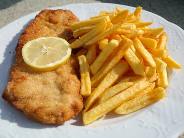 Filet de poisson pané sur assiette blanche avec frites