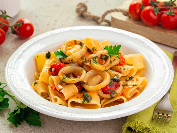 Assiette de pâtes calamarata et anneaux de calamars, sauce tomate