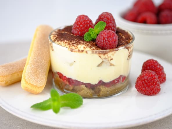 Tiramisu aux framboises en verrine sur assiette blanche