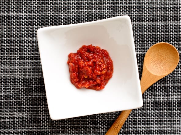 Gochujang sur fond tissé et cuiller en bois