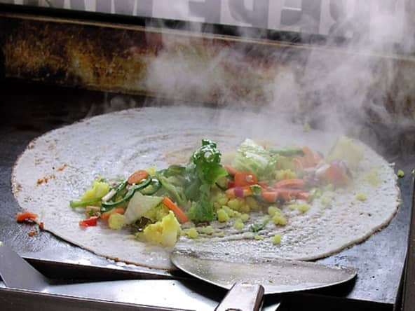 Cuisson d'un dosa garni de salade et légumes divers