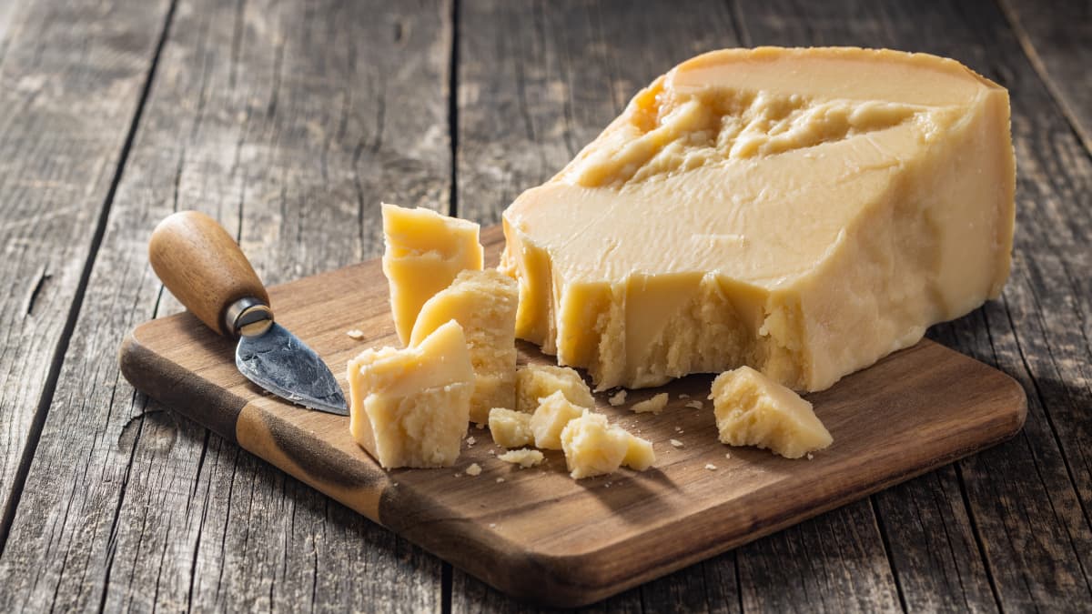 Bloc et morceaux de parmesan italien sur planche en bois