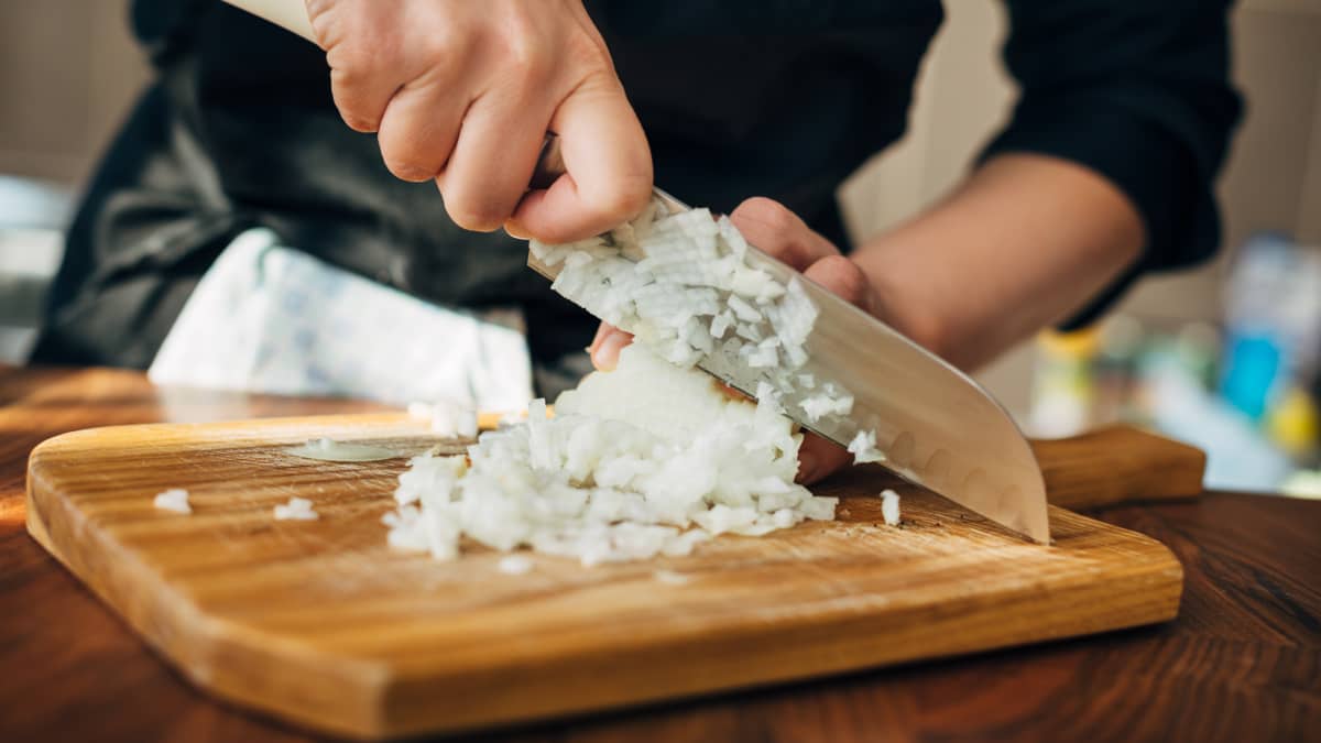 Chef cuisinier coupant des oignons sur une planche de bois