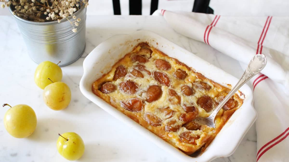 Plat de clafoutis aux mirabelles posé sur une table