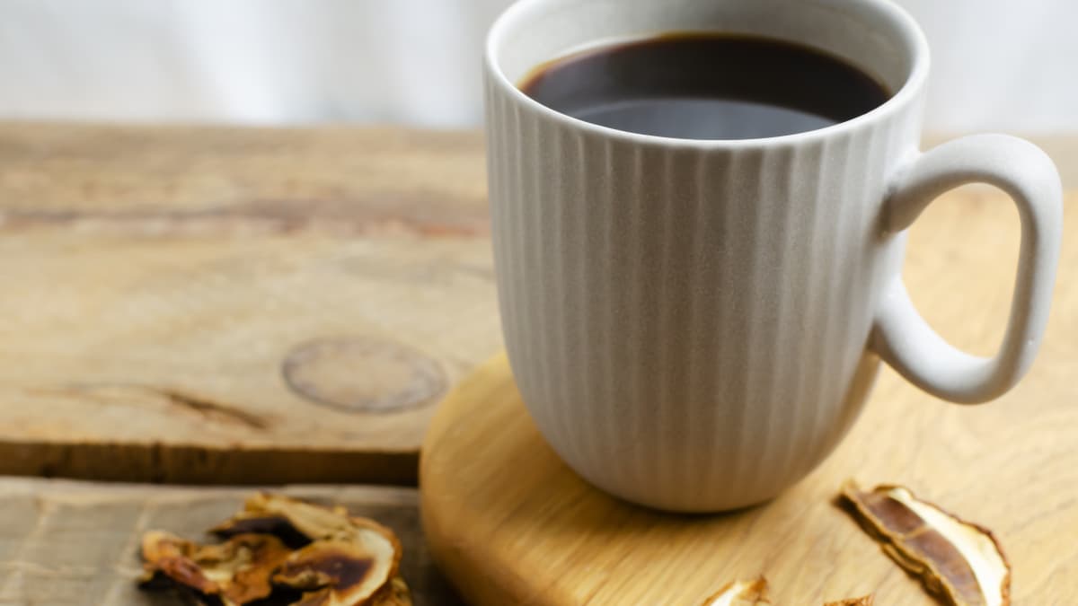 Café aux champignons dans une tasse grise sur fond bois.