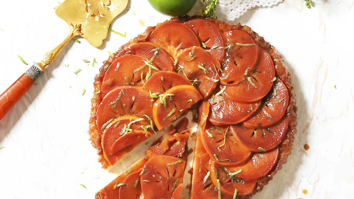 Belle tarte tatin aux kakis entière, citron vert, et pelle à tarte