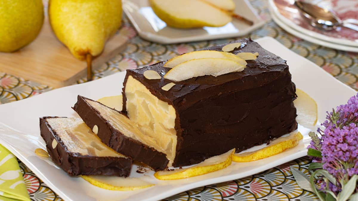 Terrine de poires Malakoff sur un plat de service blanc, poires fraîches entières et coupées