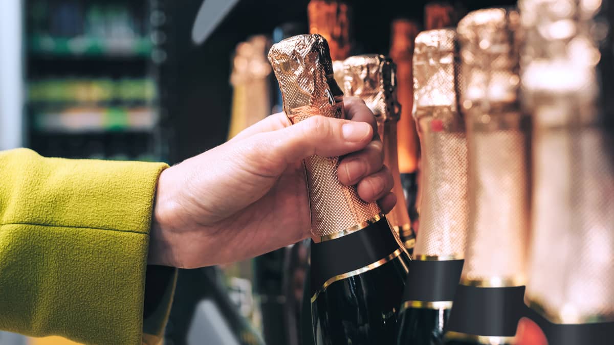 Une main prend une bouteille de champagne dans un rayon