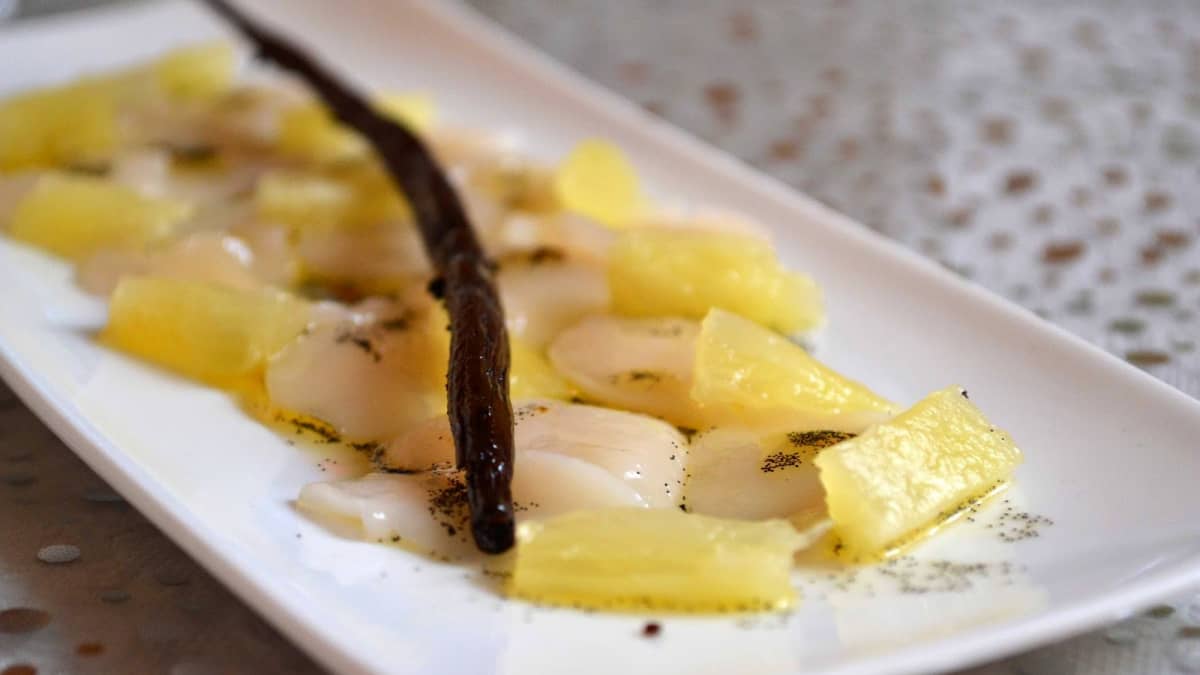 Gros plan sur une assiette de carpaccio de saint-jacques vanille ananas