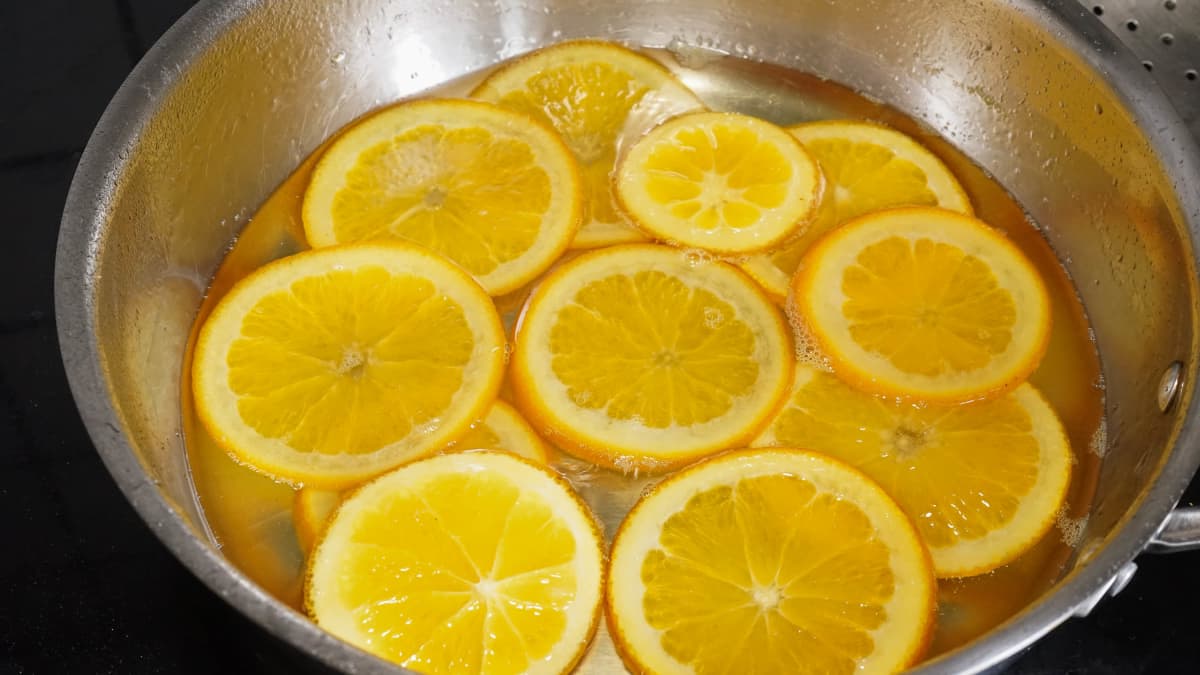 Tranches d'oranges en train de confire dans une casserole.
