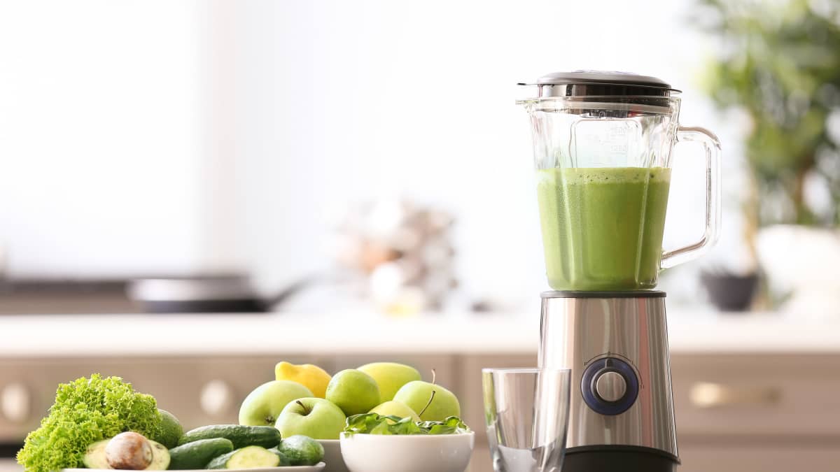 Smothie vert préparer au Blender et ingrédients frais sur une table de cuisine