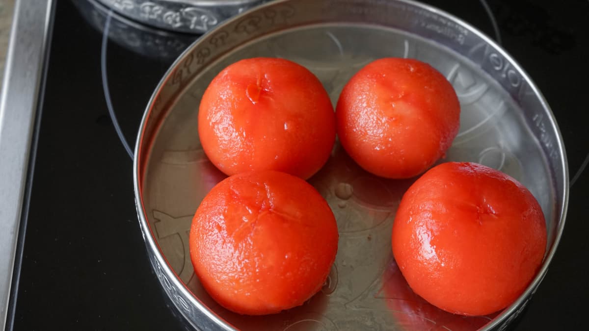 Tomates fraîchement mondées dans un plateau en fer blanc.
