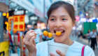 Jeune femme asiatique mangeant des fish balls dans les rues de Hong Kong