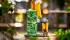 Verre de cocktail tiki posé sur un bar avec des fruits