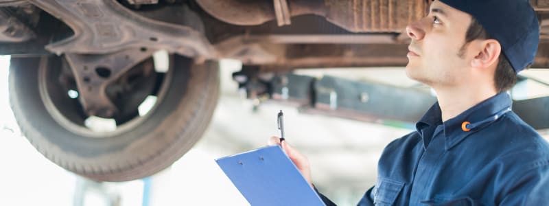 Mécanicien inspectant le châssis d'une voiture