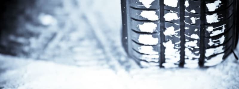 Vinterdæk på snedækket vej Sne på vejen med et bilhjul