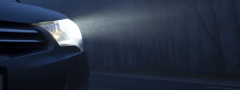 Forlygte på bil i mørket En bils forlygte lyder mørk vej op