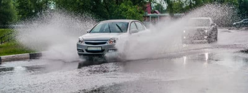 Vand kører gennem vej med meget vand Oversvømmet vej, hvor bil kører igennem