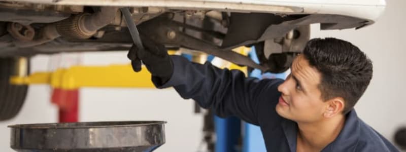 Mekaniker skifter olie på bil til service Serviceeftersyn - olien bliver bl.a. skiftet