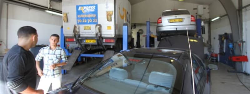 Værksted med lastbil og bil til reparation Mekanikere og biler på værksted