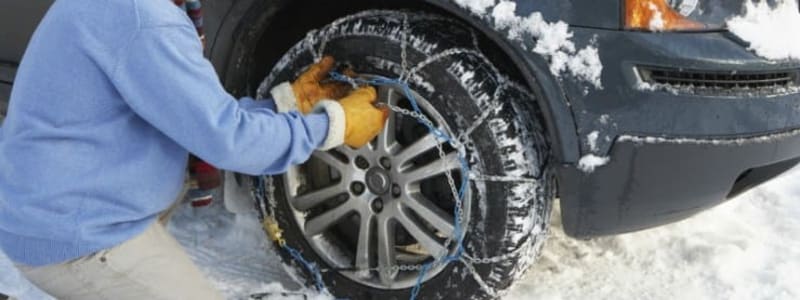 Snekæder sættes på bil Bil i sneen og mand der sætter snekæder på