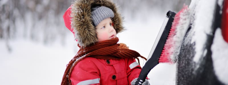 Les accessoires automobiles à avoir pour l'hiver Enfant aidant à déneiger une voiture
