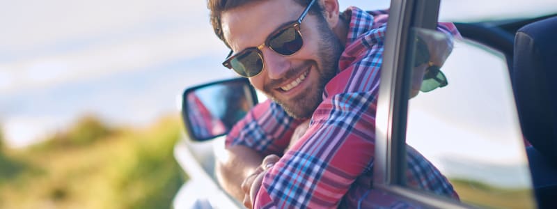 Ce que vous devriez faire avant de partir en vacances cet été Homme dans sa voiture partant en vacances