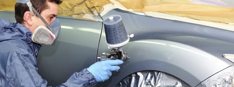 Conseils pour protéger la peinture de votre véhicule Homme effectuant des retouches de peinture sur la carrosserie d'une voiture