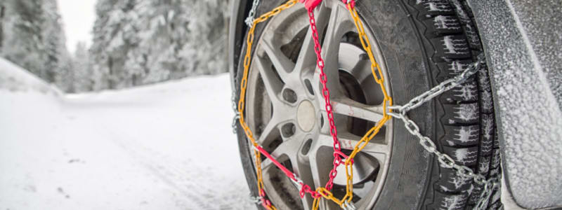 Pourquoi installer des chaînes à neiges sur les roues de ma voiture ? Voiture sur une route enneigée