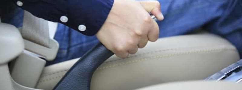 Conducteur activant le frein à main de sa voiture