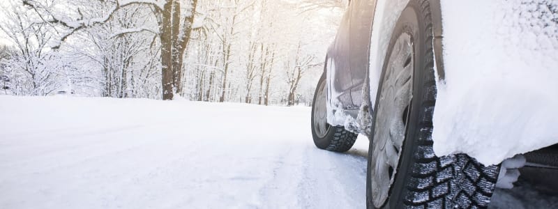 Pourquoi installer des chaînes à neiges sur les roues de ma voiture ? Voiture sur une route enneigée