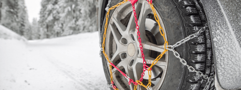 Pourquoi installer des chaînes à neiges sur les roues de ma voiture ? Voiture sur une route enneigée