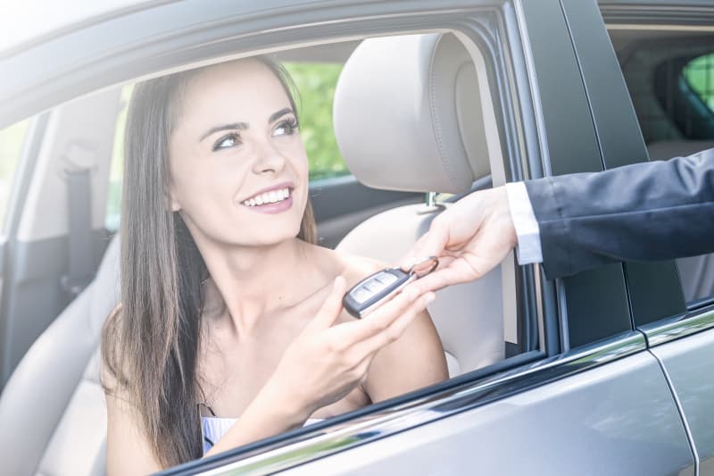 Absorber les coûts de l'entretien de votre voiture Jeune femme prenant les clés de sa nouvelle voiture