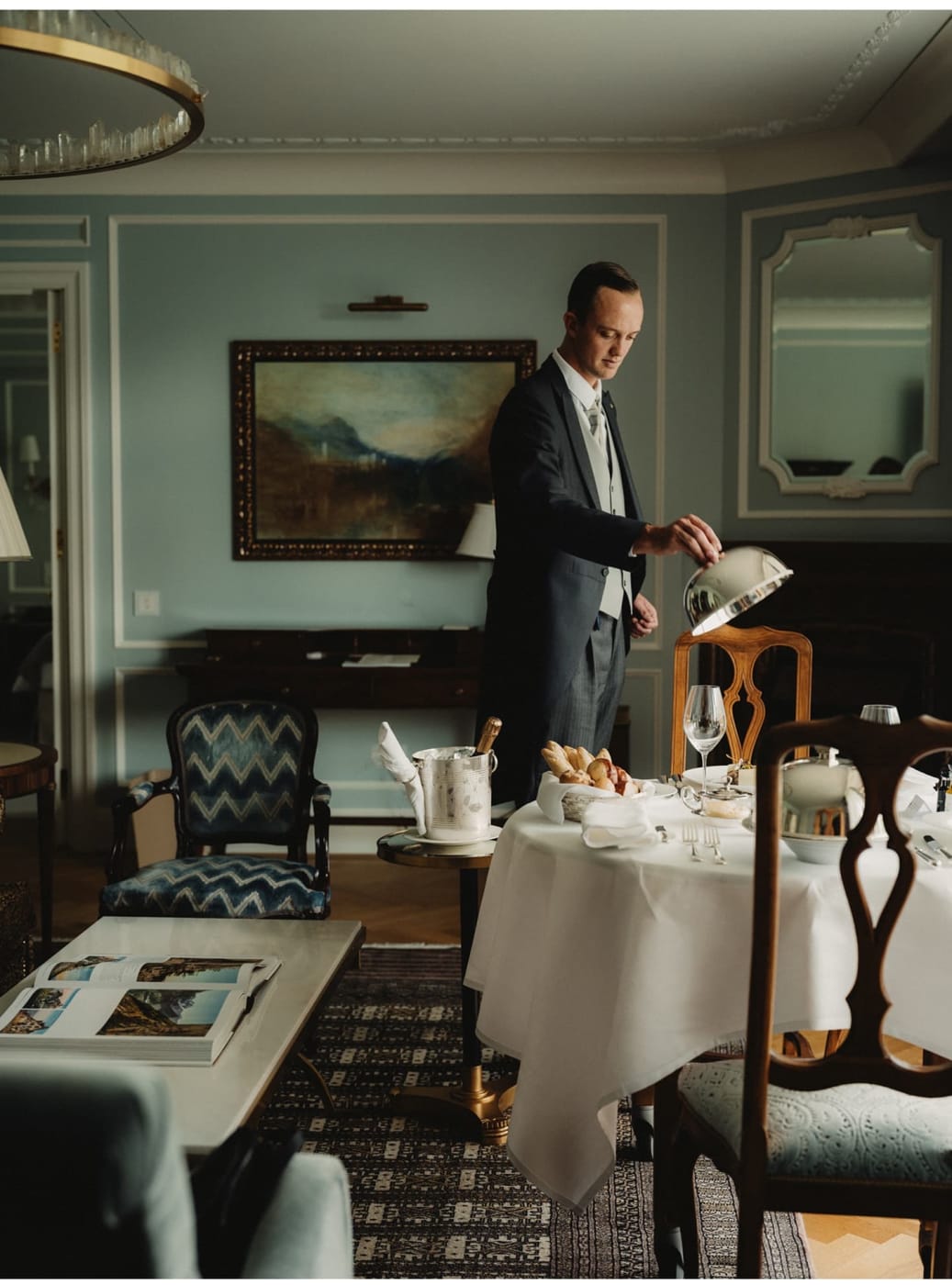 Ein Butler hebt eine Silberglocke, um in einer Suite des Badrutt's Palace das Frühstück zu servieren