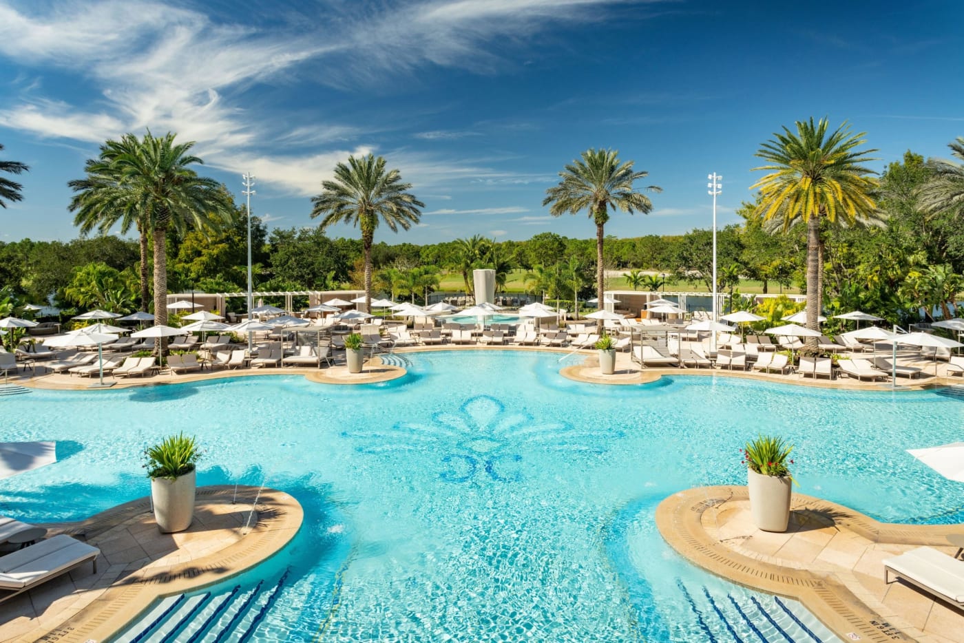The large outdoor pool at The Ritz-Carlton Orlando, Grande Lakes, lined with palms and loungers