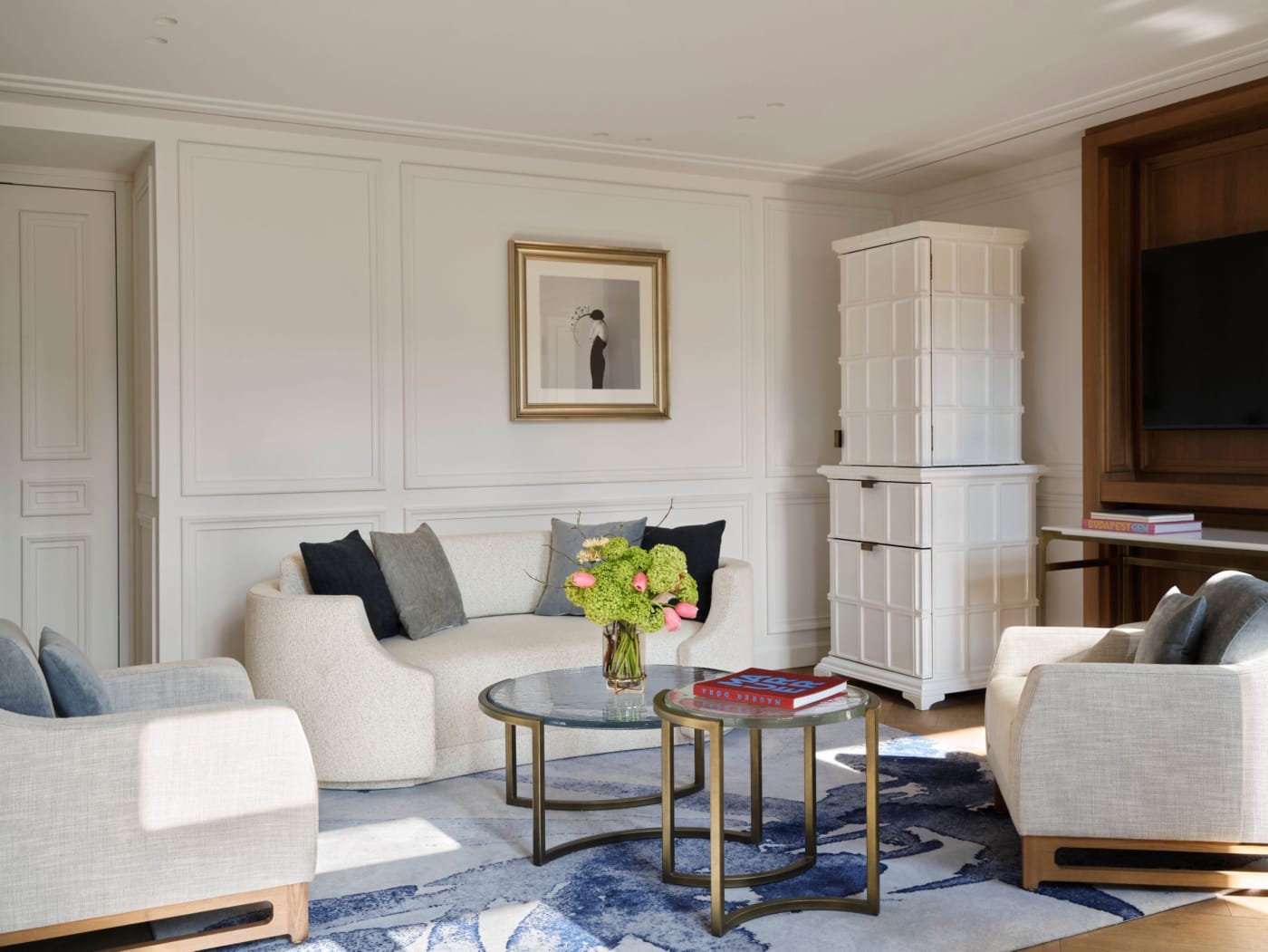 The living room of the two-bedroom duplex suite at The St. Regis Budapest, with white panelling and a tiled stove