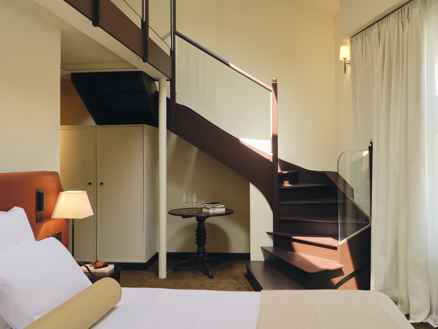 Une chambre en duplex de la Villa Florentine à Lyon, escalier en bois sombre et voilages
