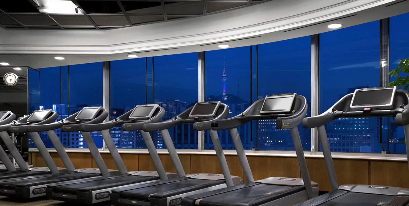 El gimnasio del hotel The Plaza en Seúl, con ventanales hacia la torre Namsan de noche