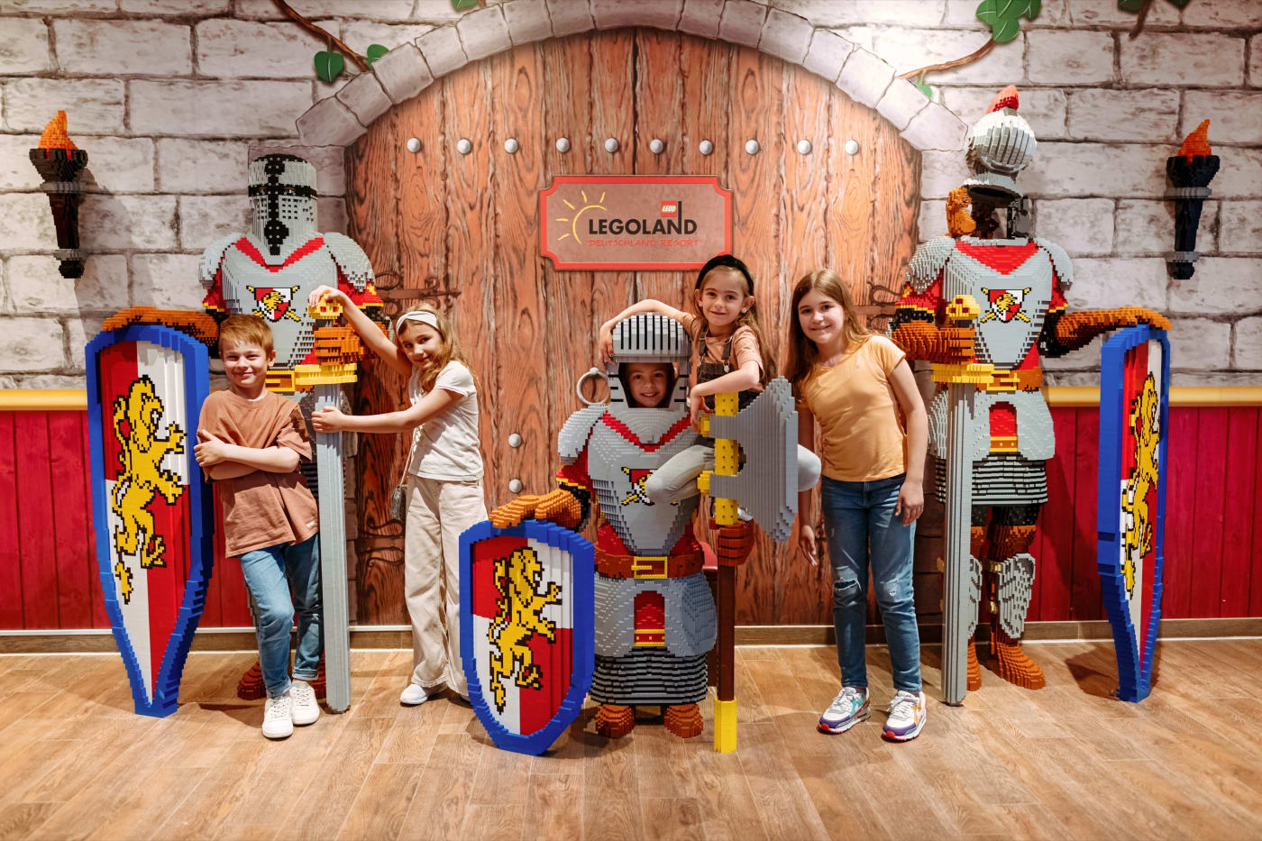 Children in armour in the lobby of a Legoland Deutschland castle hotel, among LEGO knights